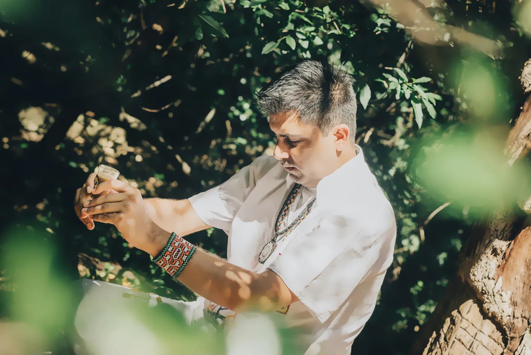 Jayesh Mitha holding a ceremonial cup among the trees in Cape Town